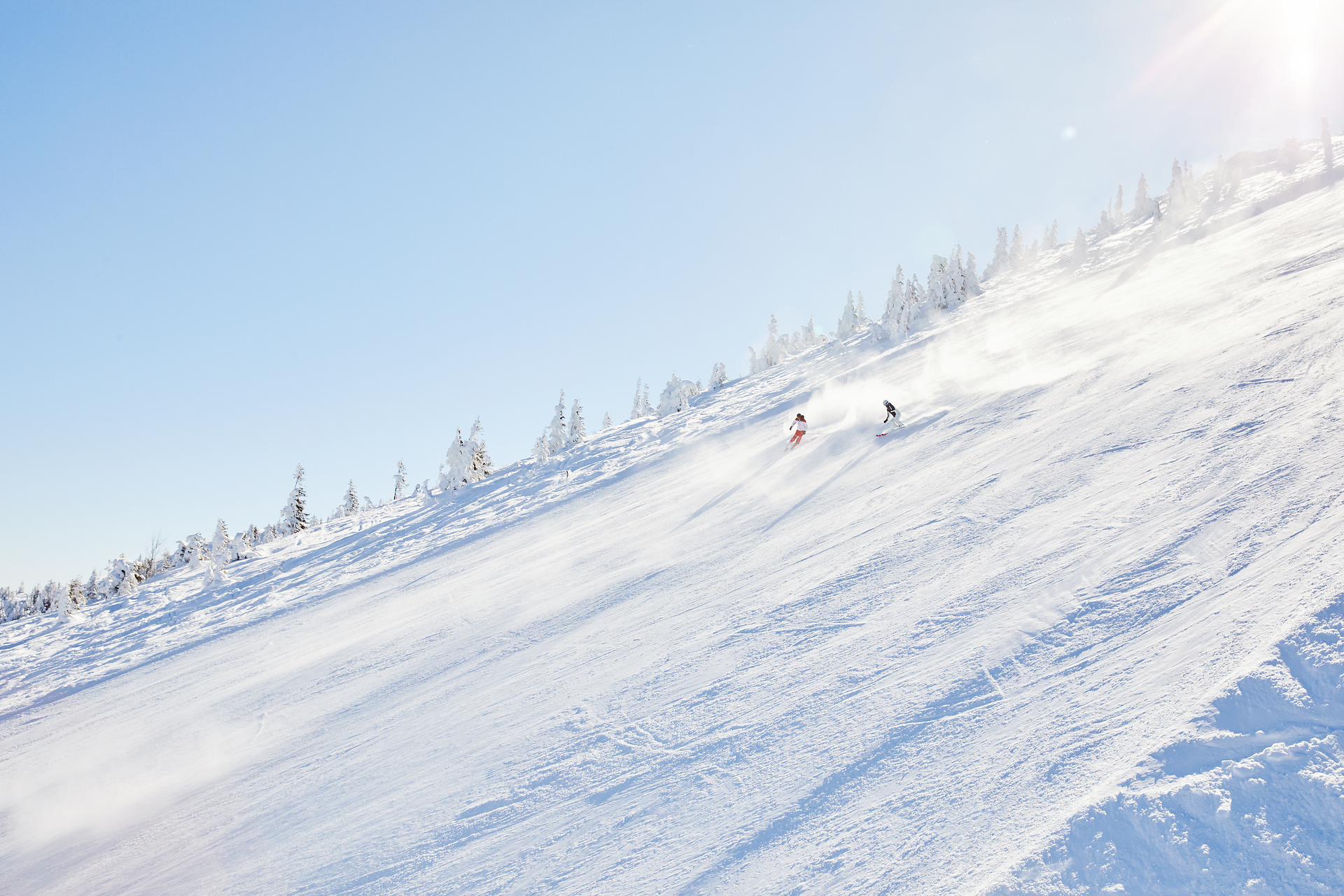 Die glitzernde Schneedecke erstreckt sich majestätisch über die sanften Hänge, während die Sonne strahlend am Himmel steht. Skifahrer gleiten elegant durch den frischen Pulverschnee und genießen die atemberaubende Aussicht auf die umliegenden Berge. Ein perfekter Tag im Winterparadies, wo Abenteuer und Natur harmonisch verschmelzen.