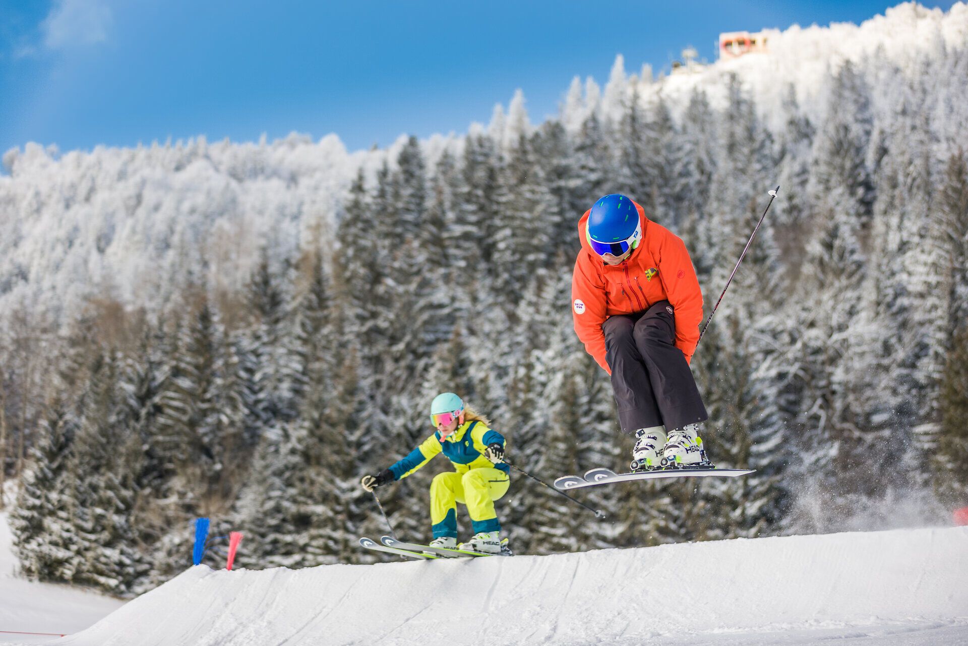 Die frische Winterluft erfüllt die Atmosphäre, während zwei Skifahrer mit Freude über die schneebedeckte Piste gleiten. Umgeben von majestätischen, verschneiten Bäumen und strahlend blauem Himmel, erleben sie den perfekten Tag im Schnee. Hier in Annaberg wird der Winter zum unvergesslichen Abenteuer.
