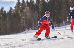 Ein fröhliches Kind gleitet mit Schwung über die schneebedeckten Pisten, während die strahlende Wintersonne den glitzernden Schnee erleuchtet. Umgeben von majestätischen Bergen und dichten Wäldern, wird hier der Wintertraum lebendig. Die frische, kalte Luft und das Lachen der Skifahrer schaffen eine unvergessliche Atmosphäre.